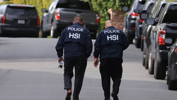 Homeland Security Investigations agents walk outside one of the properties on Monday