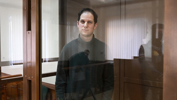 Evan Gershkovich looks out from inside a defendants' cage before a hearing at the Moscow City Court in Moscow on 20 February