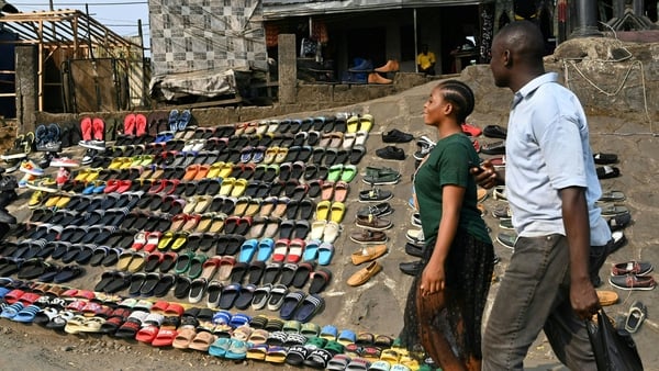 Pedestrians walk past a street vendor's shoe display near Buea in Cameroon. The city has been at the centre of one of Africa's bloodiest conflicts since 2016. Photo: Issouf Sanogo/AFP via Getty Images
