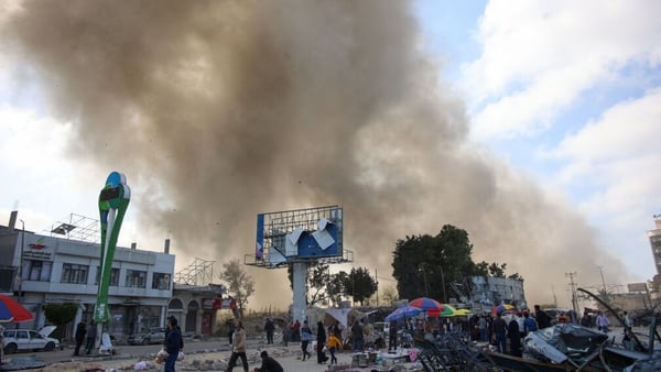 Palestinians look at smoke billowing during Israeli bombardment on the Firas market area in Gaza City