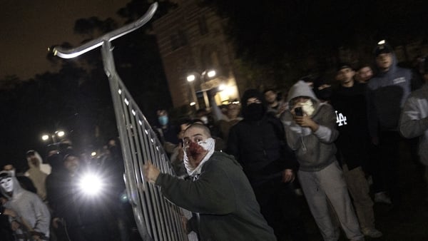 A counter protester throws a fence at pro-Palestinian protesters on the UCLA campus