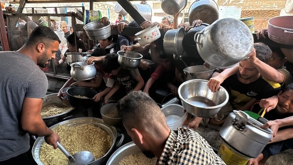 People queue to receive food from charities in Rafah, southern Gaza