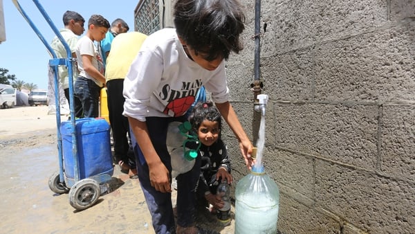 Children collect water in Deir Balah, Gaza