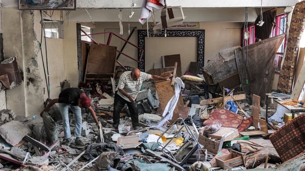 A man and a boy inspect items to be salvaged from a heavily damaged room at a school in Gaza City