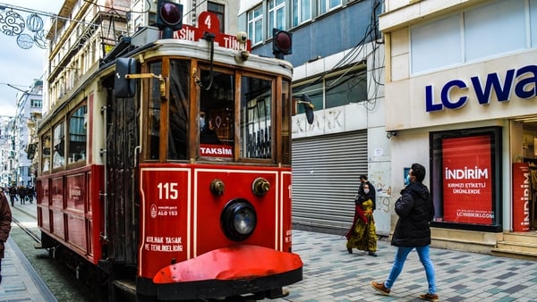 People walk past an emblematic red and white tram on Istiklal Street