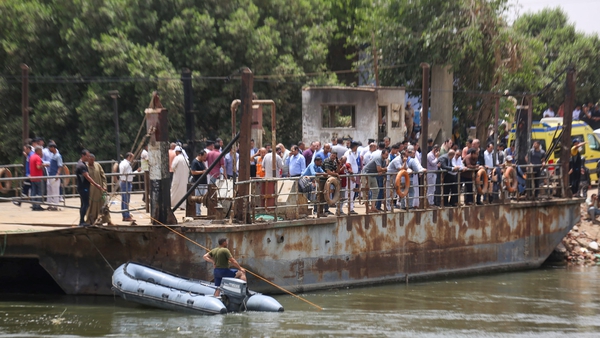 Relatives wait on the bank of a canal of the Nile River as rescuers search the waterway
