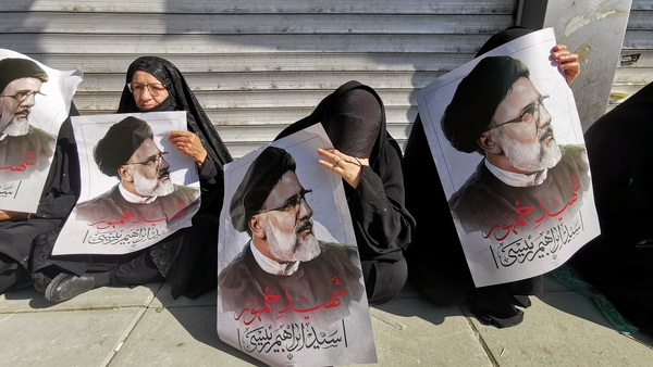 Mourners hold posters of Iranian President Ebrahim Raisi during a funeral ceremony for him and his companions who were killed in a helicopter crash