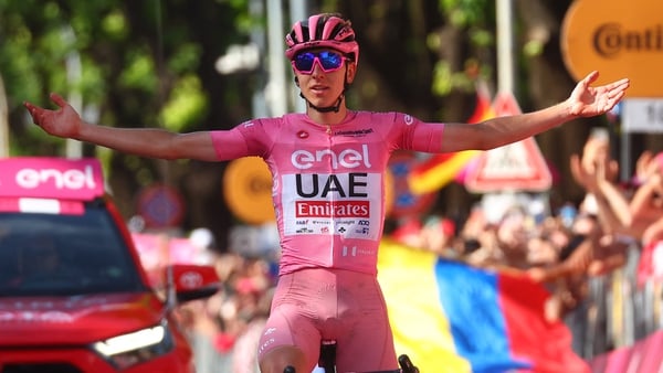 Tadej Pogacar wearing the overall leader's pink jersey celebrates as he crosses the finish line to win the 20th stage
