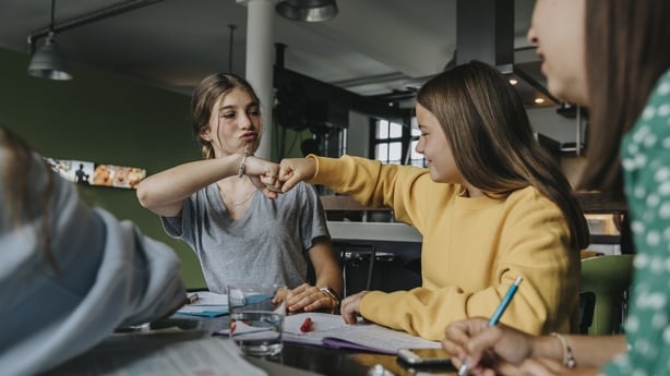 Teenage girls studying together at home, doing fist bump