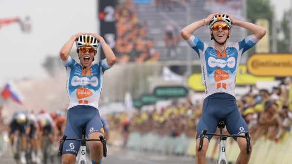 Romain Bardet cycles to the finish line ahead of Team DSM-Firmenich PostNL team-mate Frank Van Den Broek (L) to win the first stage