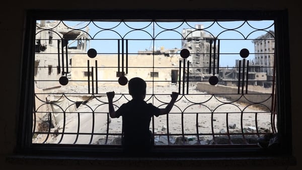 A Palestinian child looks out of the window of a home damaged from previous Israeli bombardment in southern Gaza