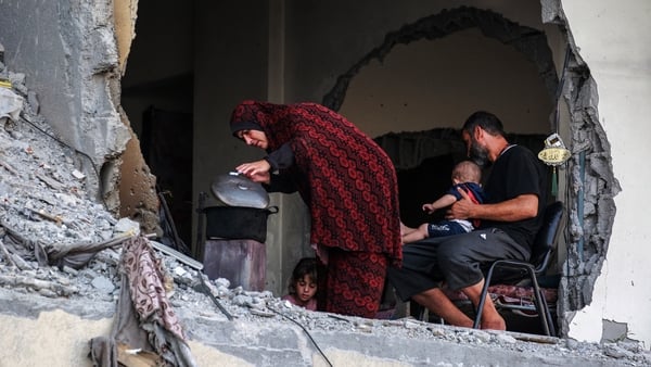 A family gathers around a makeshift wood stove in a damaged building in Khan Younis