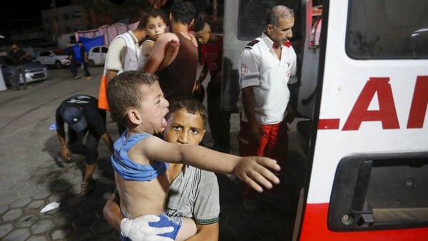 A young boy carries an injured child into Al Aqsa Martyrs Hospital in Deir al Balah for treatment