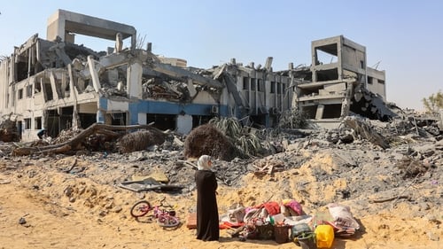 A woman looks around as she salvages items at the damaged UNRWA building complex in western Gaza City's Al-Sinaa neighbouhood