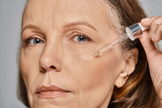 Older woman applies serum to her face 