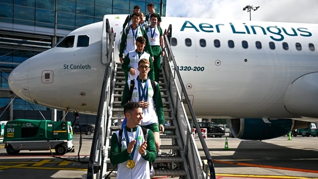 Treoraíonn an Gymnast Rhys McClenaghan, a bhuaigh an t-ór san imeacht capall pommel, a chomhpháirtithe den eitleán