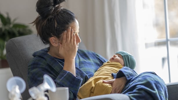 Depressed young woman with cuddling baby at home
