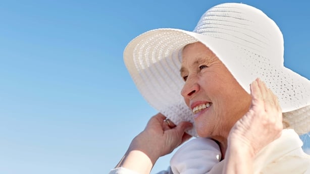 Old woman smiles into the sun with hat on