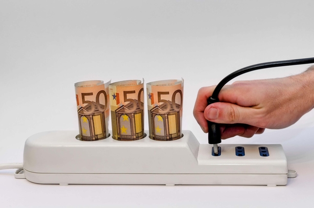 Power strip with money, white background and an hand holding a plug