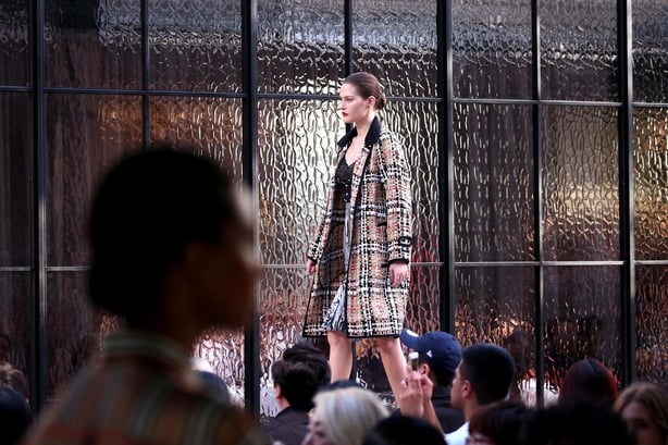 Model walks on runway in Burberry woollen tweed duster coat