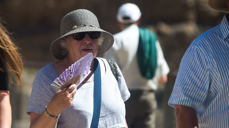 A woman wearing a hat to protect herself from the sun uses a fan during a hot day in Malaga last month