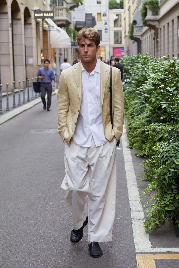 Man walks down street in white shirt and beige jacket and trousers