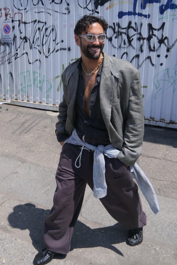 Man walks across street in oversized blazer and trousers with sunglasses and messy hair