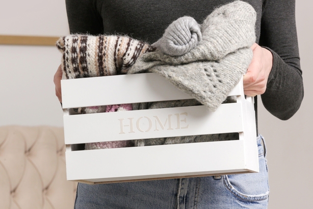 Woman holding wooden box with warm clothing