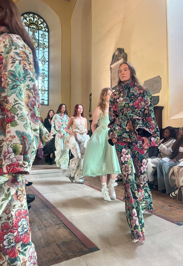 Model walks down runway in floral trousers