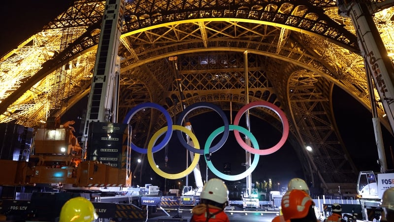 Workers remove Olympic rings from the Eiffel Tower