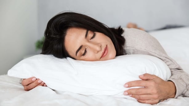 Photo of woman in her 30s with dark hair sleeping in bed