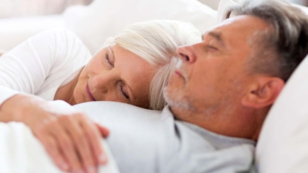 Senior man and woman cuddling in bed together struggling to sleep