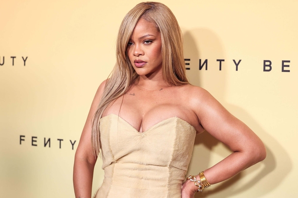 Rihanna poses in front of Fenty Beauty sign