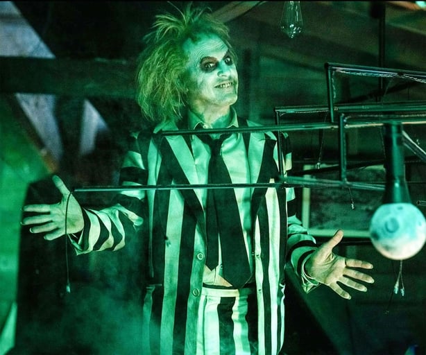 Beetlejuice poses in black and white pinstripe suit