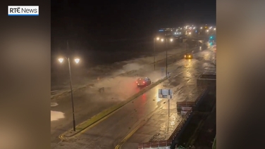 Motorists drive along Galway road as waves crash during Storm Ashley