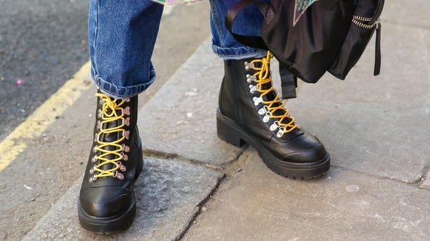 Person wears black lace up boots with yellow laces