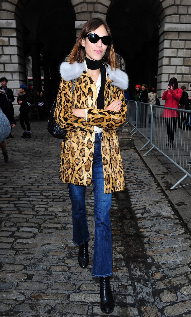 Alexa Chung walks through street in leopard print jacket with fur lilac collar and denim jeans
