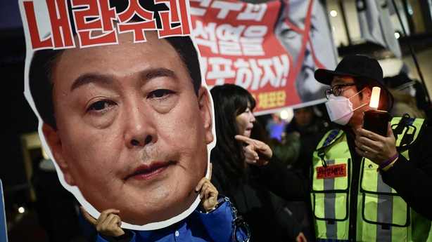 A protester holding a placard reading 'Leader of insurgents' on an image of President Yoon Suk Yeol