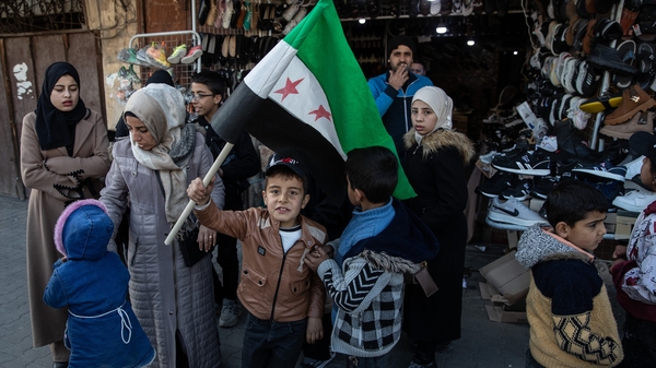 A boy waves the new Syrian flag at a shopping street in Aleppo, Syria