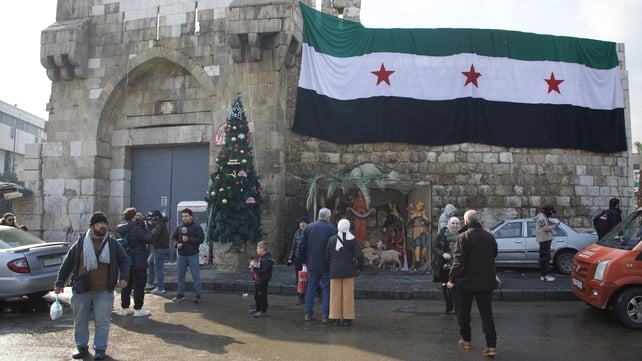 The Syrian flag hangs above a Nativity scene and Christmas Tree on New Year's Eve in Damascus, Syria