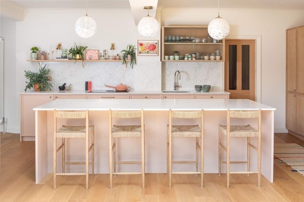 Soft-hued plaster pink kitchen paired with oak veneered cabinets creates a calming, sanctuary-like space.