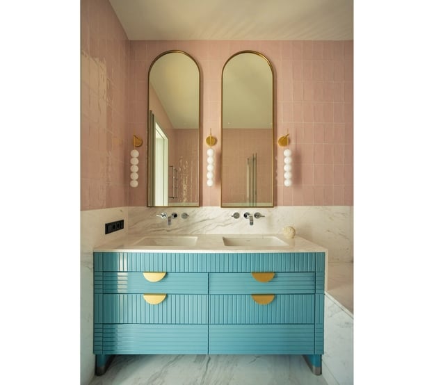 A stylish contemporary bathroom pairs a pastel backsplash with a boldly coloured statement vanity unit