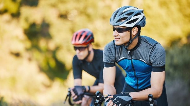 Active senior couple with electrobikes standing outdoors on a road in nature.