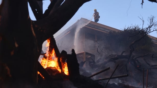 A firefighter battles flames in Pacific Palisades