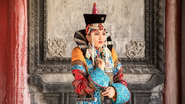 Young Mongolian woman in a traditional 13th century costume in a temple.