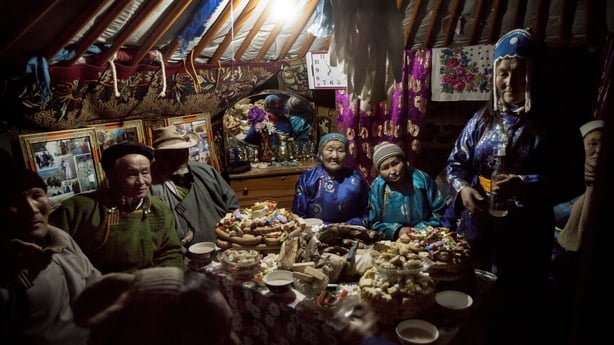 A Tuvan family sit before a feast to celebrate Lunar New Year, Tsagaan Sar in their ge