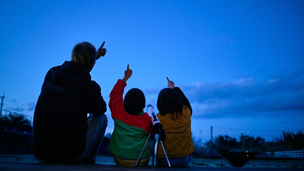 Silhouette of father and son pointing to sky