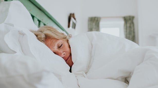 A senior woman sleeping peacefully under a blanket