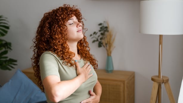Two senior women sat at home doing breathing exercises together