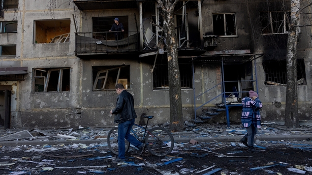 People walk by a damaged residential building following a strike in Dobropillia